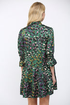 Back view of a woman wearing a green background  patterned dress on a white background