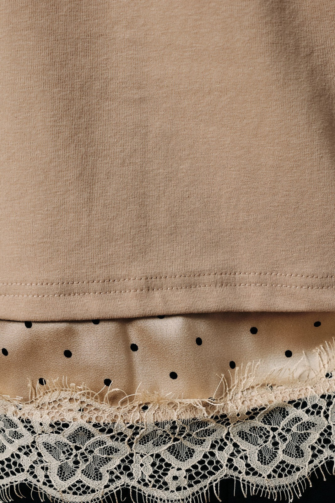 Close-up of a taupe knit garment with lace and satin trim at the bottom.