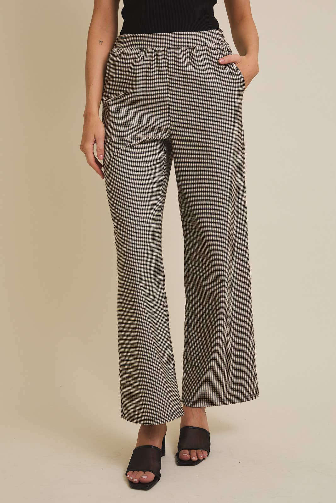 Woman wearing checkered pants on a beige background