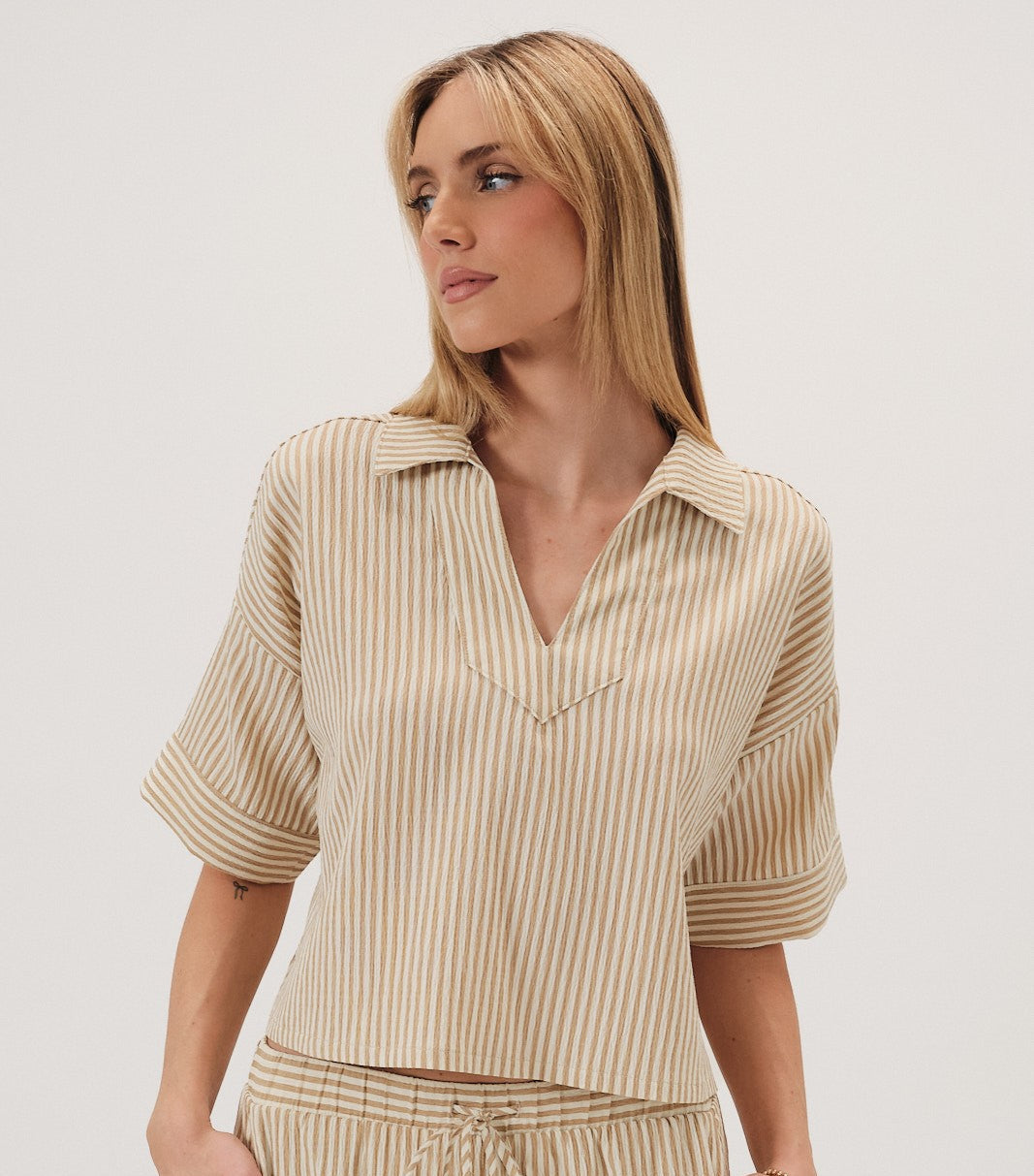 Woman wearing a beige striped top on a white background