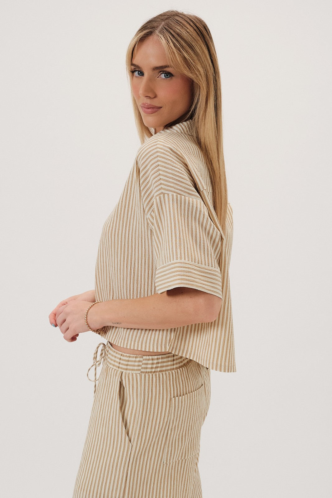Woman wearing a beige striped top on a white background