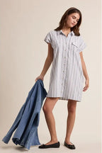 A woman wearing a striped shirt dress on a beige background