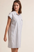 A woman wearing a striped shirt dress on a beige background