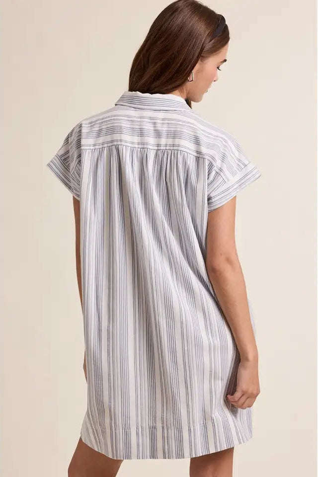 Back view of a woman wearing a striped shirt dress on a beige background