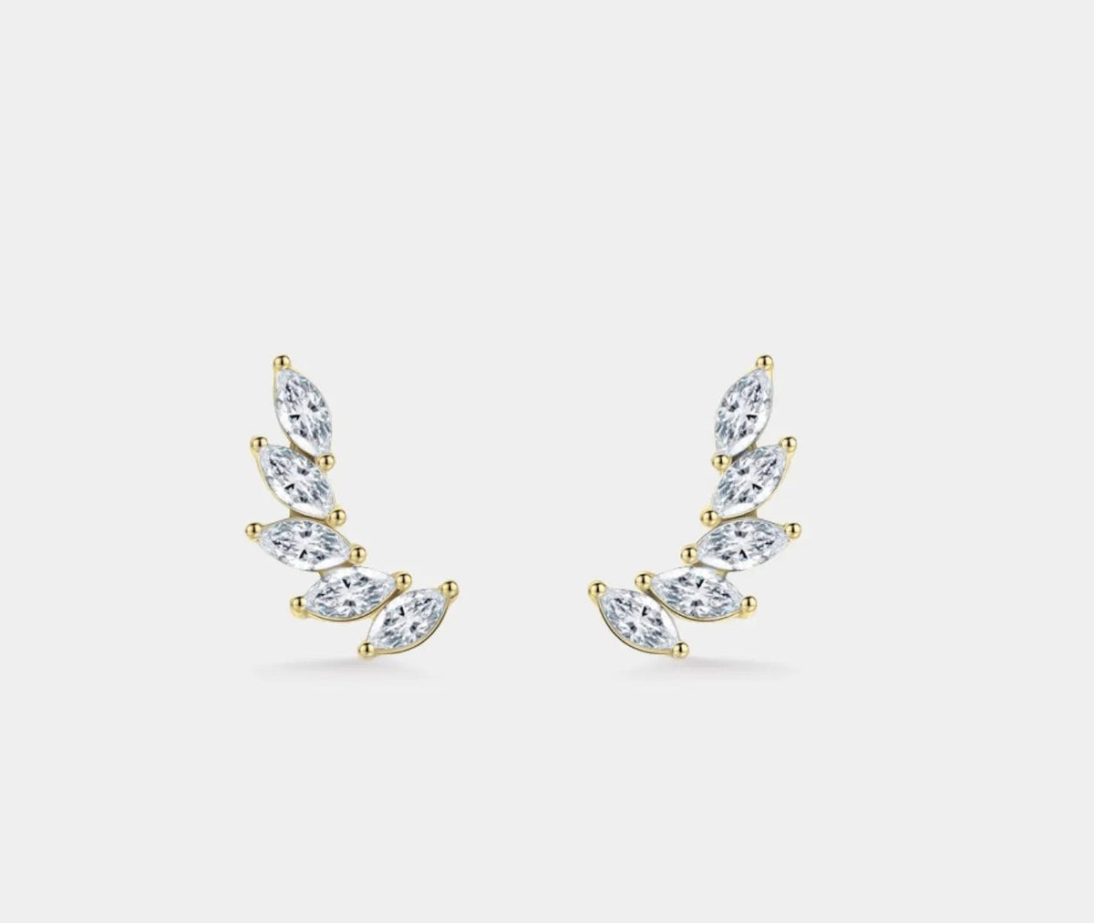 A pair of gold plated crescent-shaped stud earrings set with marquise-cut cubic zirconia, displayed on a light gray background.