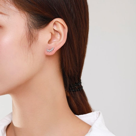 Woman wearing a pair of silver plated crescent-shaped stud earrings set with marquise-cut cubic zirconia.