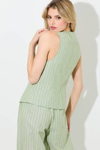 Woman wearing a matcha and ivory pinstripe button vest and pants on a grey background