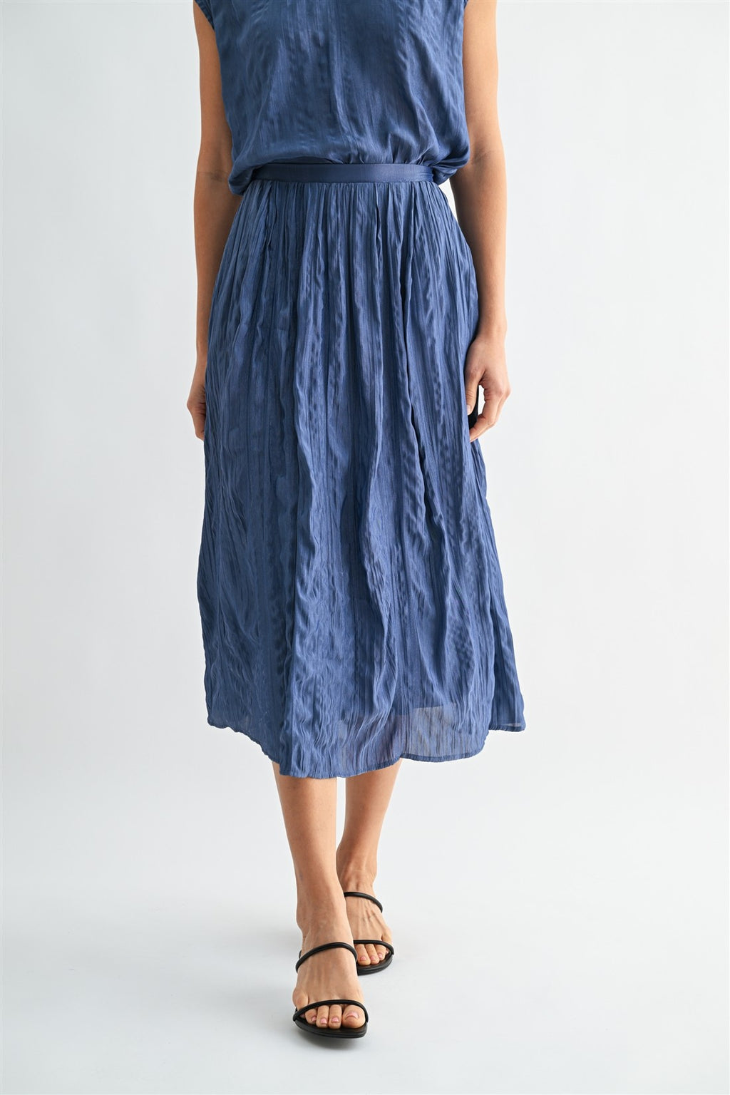 Woman wearing a dusty blue skirt on a white background