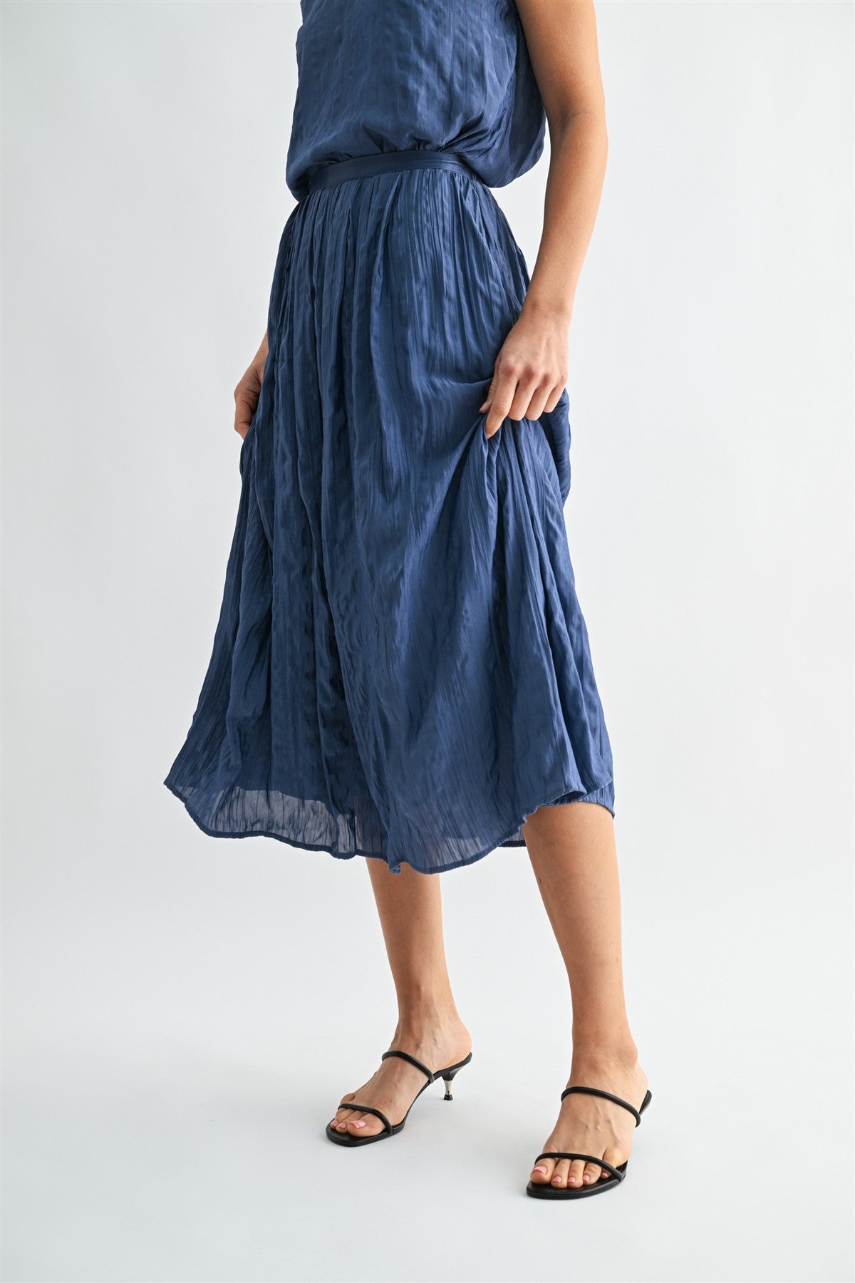 Woman wearing a dusty blue skirt on a white background