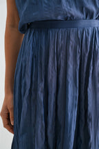 Close up of a woman wearing a dusty blue skirt on a white background