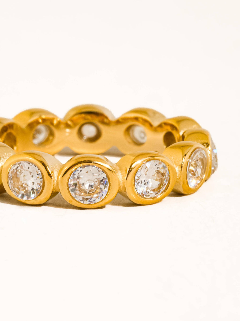 A gold plated eternity-style ring with round cubic zirconia set in a repeating pattern, photographed on a clean white background.