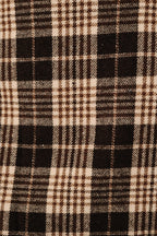 A close-up of a plaid fabric pattern with alternating blocks of black and warm cream, detailed with thin brown and beige intersecting lines.