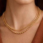 Woman wearing a gold tone triple chain bead necklace 