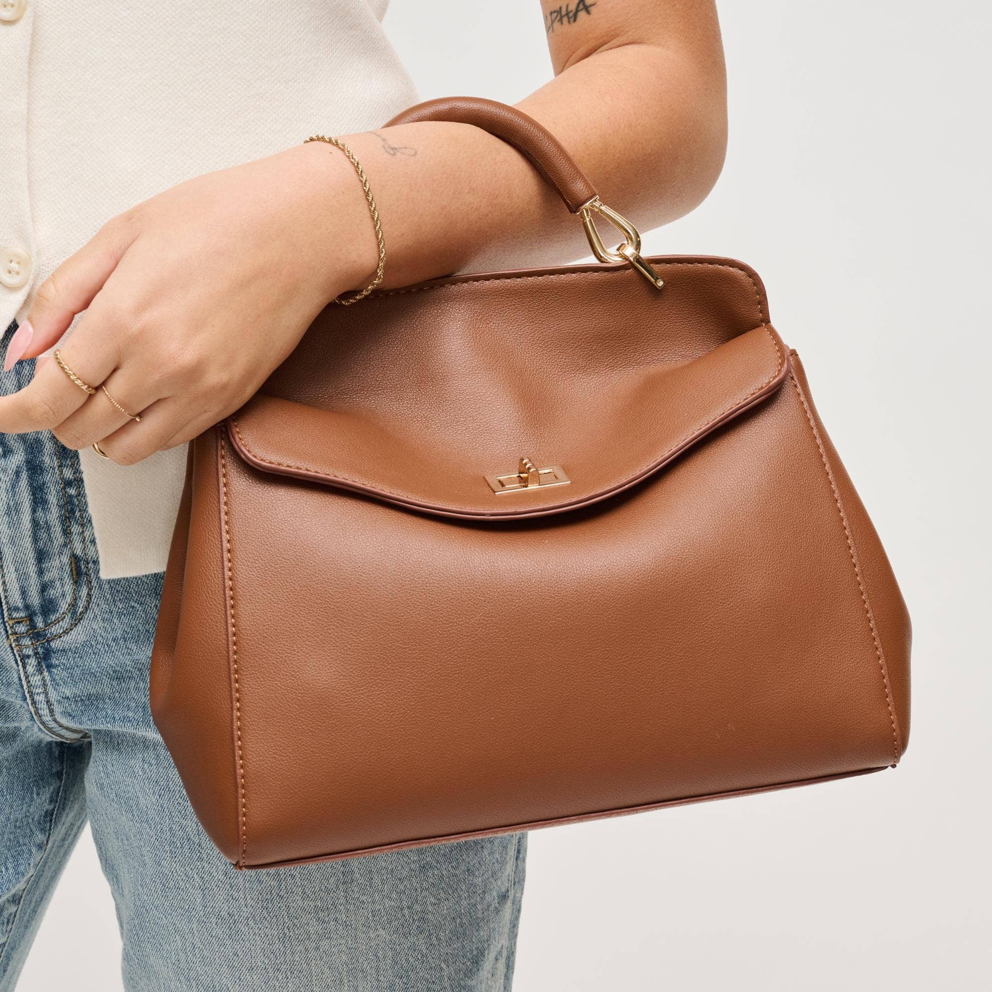 Brown vegan leather handbag/crossbody with curved flap and gold hardware on a white background