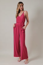 Woman wearing a fuchsia jumpsuit on a plain background