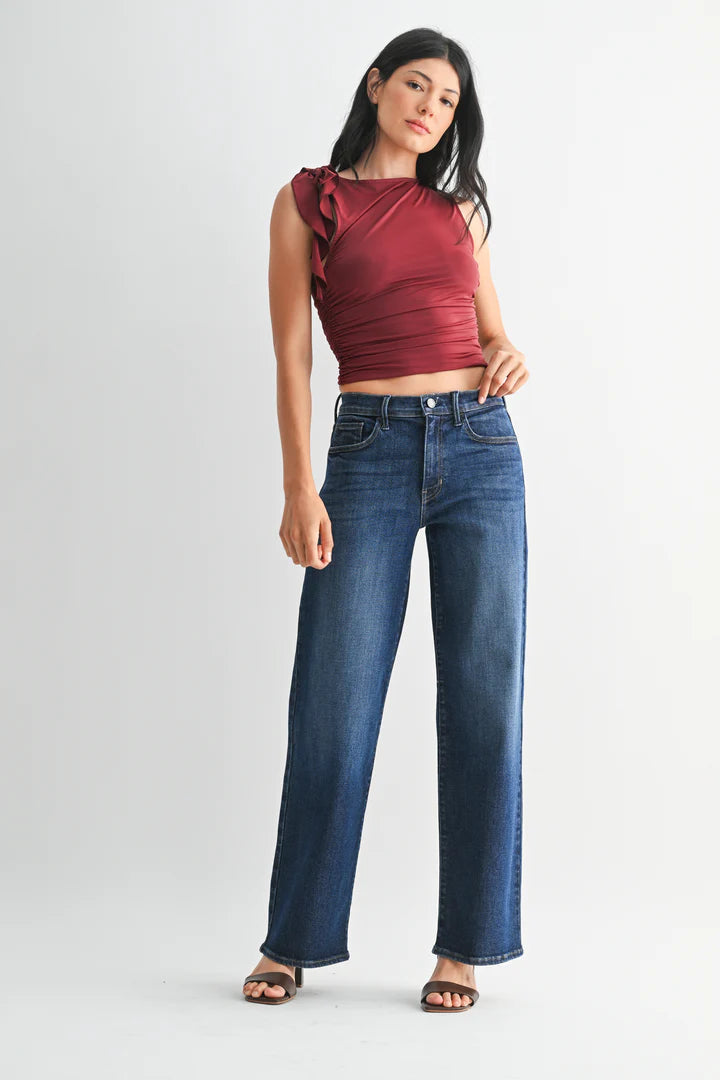 Woman wearing a red top and dark wash jeans on a white background