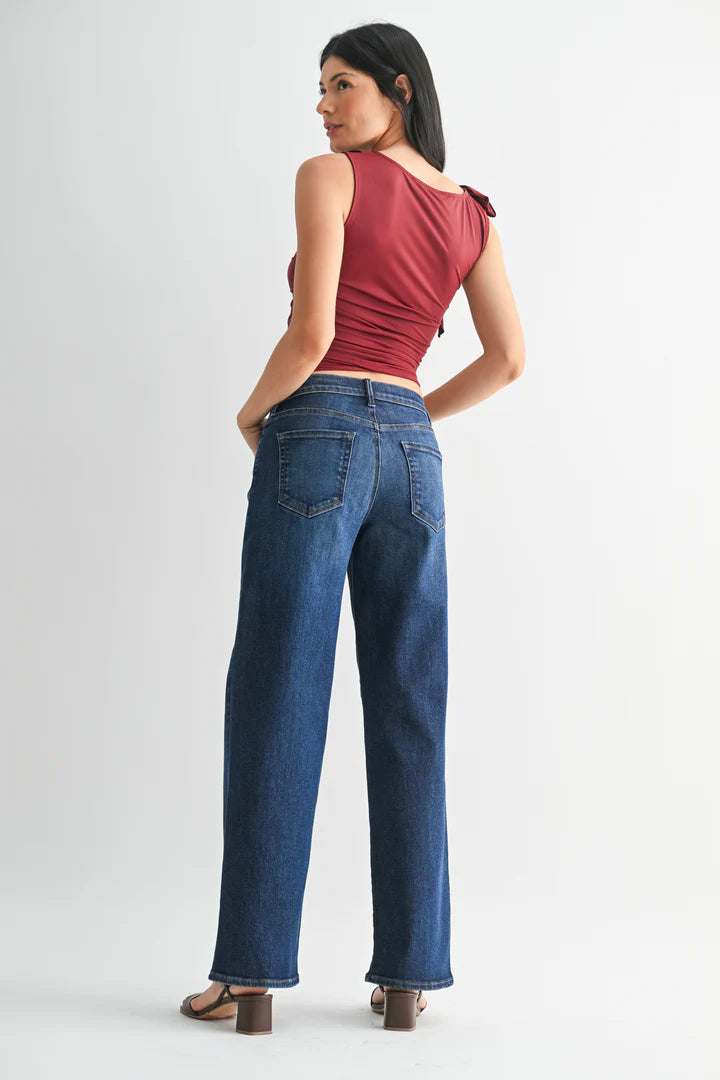 Woman wearing dark wash jeans and a red top on a white background