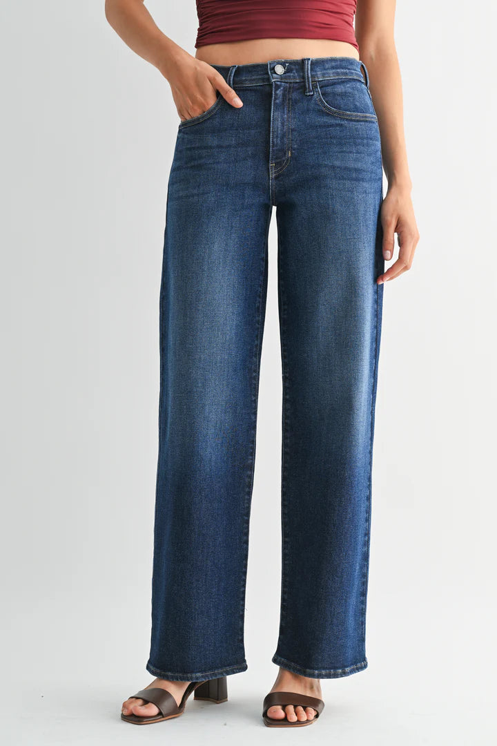 Woman wearing dark wash jeans on a plain background