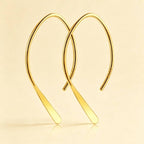 Gold plated open arch threader earrings against a beige background