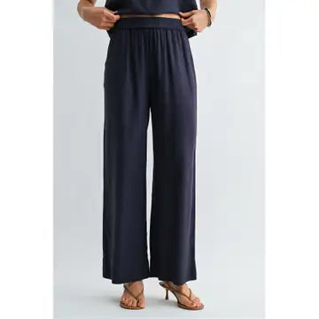Woman wearing navy wide-leg pants on a light gray background