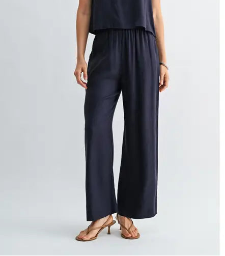 Woman wearing a navy wide-leg pants on a light gray background