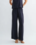 Woman wearing navy wide-leg pants on a light gray background