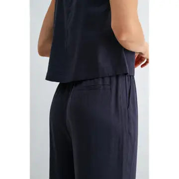 Back view of a woman wearing navy pants on a light gray background