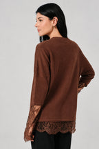 Back view of a woman wearing a small ribbed brown shirt with lace sleeves and hem against a white drape background