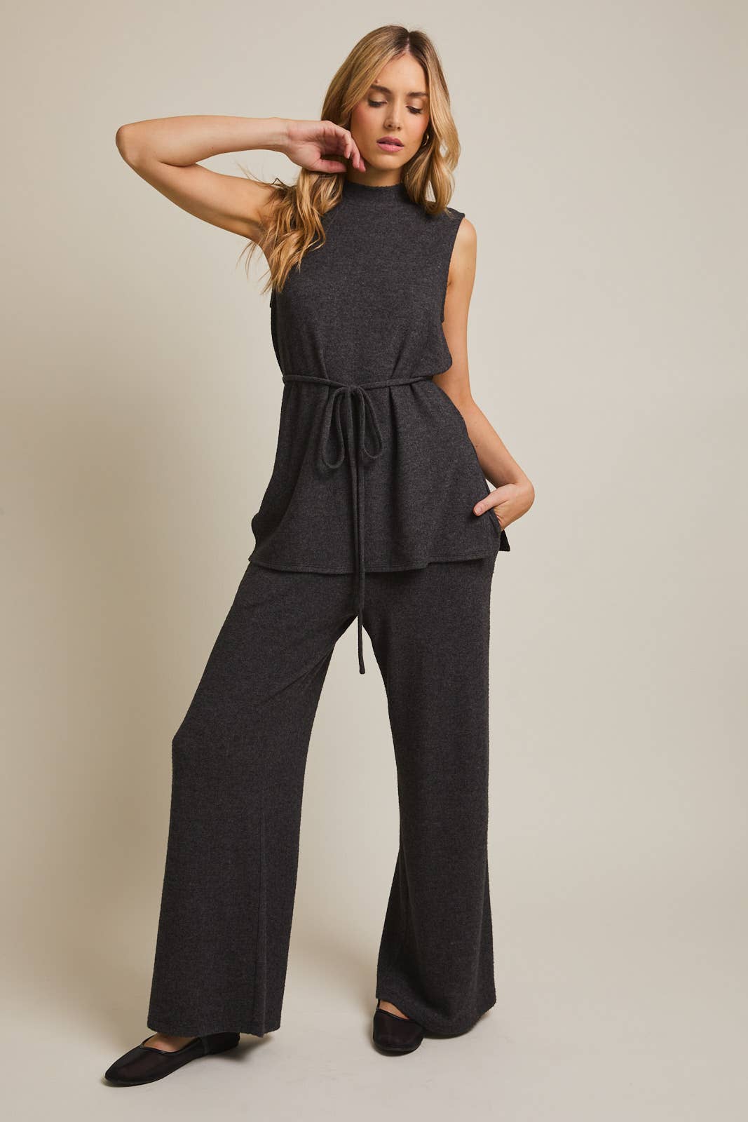 Woman wearing a heather  gray sleeveless top and wide-leg pants against a beige background