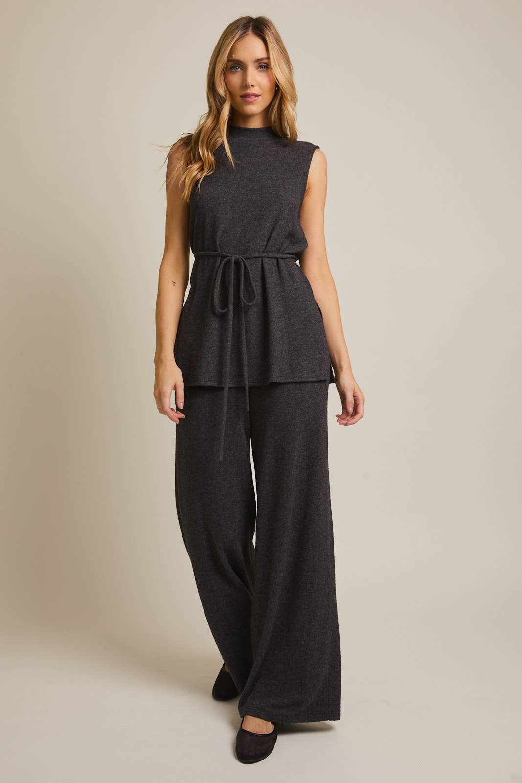 Woman wearing a heather gray sleeveless top and wide-leg pants on a beige background