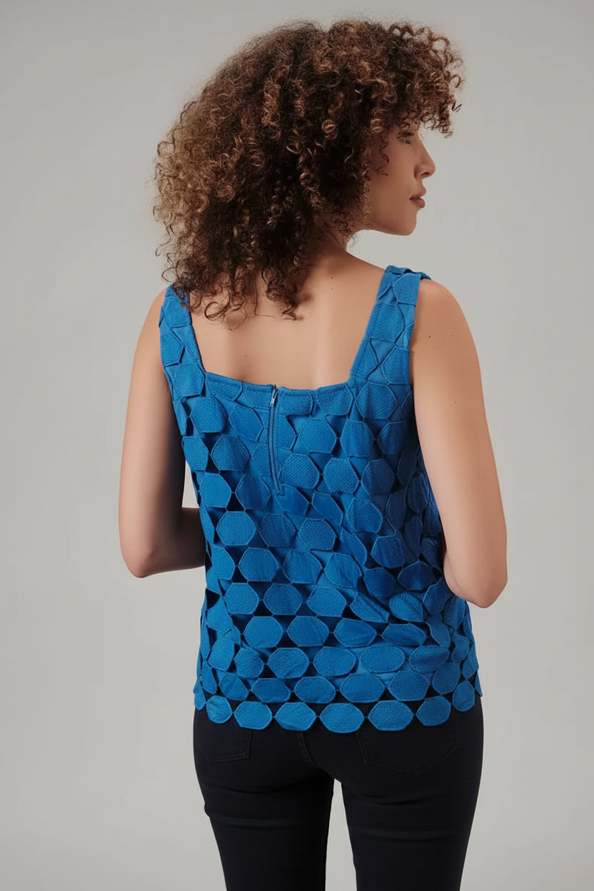 Back view of a woman wearing a blue sleeveless top with a lace applique overlay against a beige background