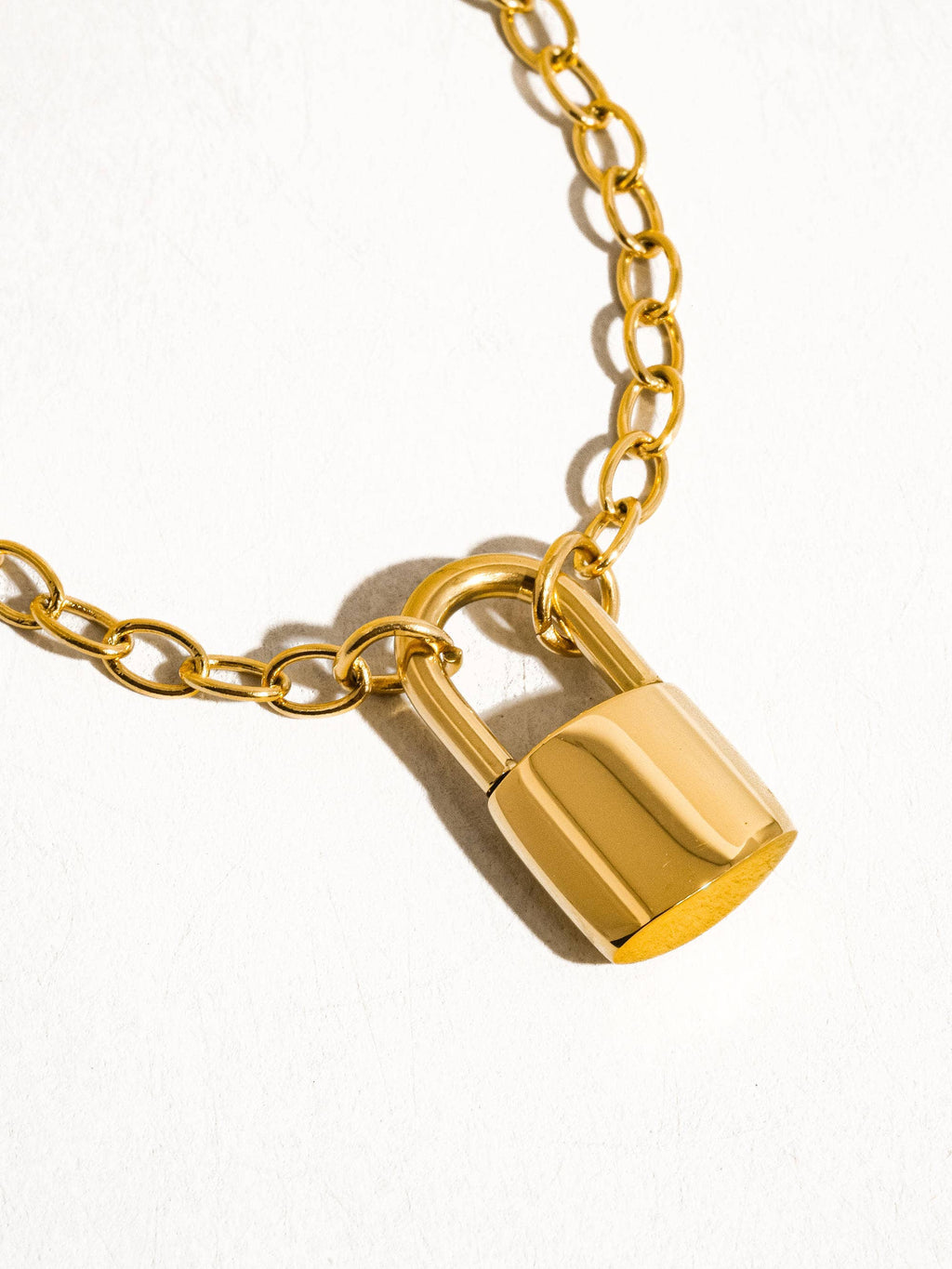 Gold lock pendant on a gold chain against a white background