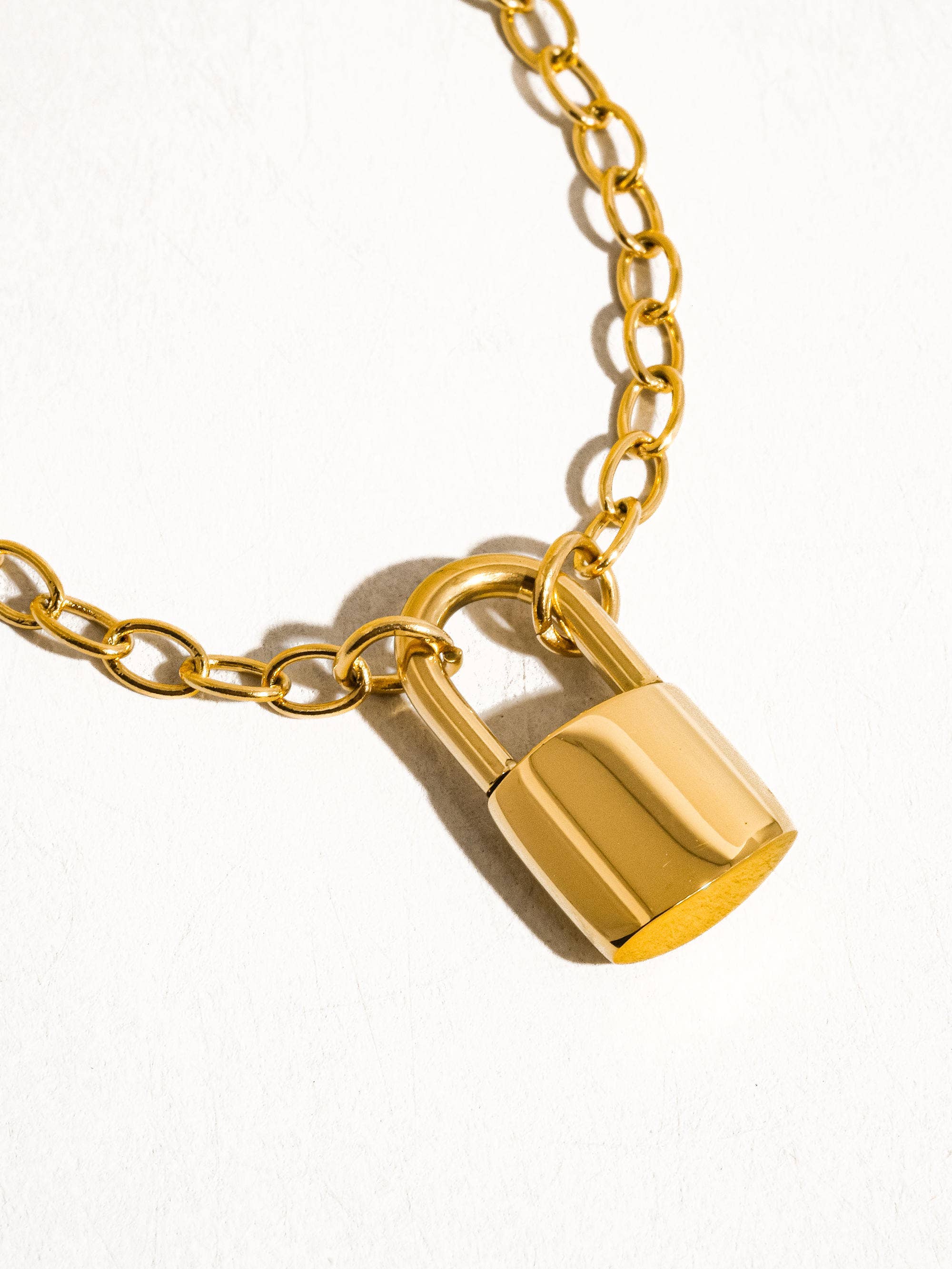 Gold lock pendant on a gold chain against a white background
