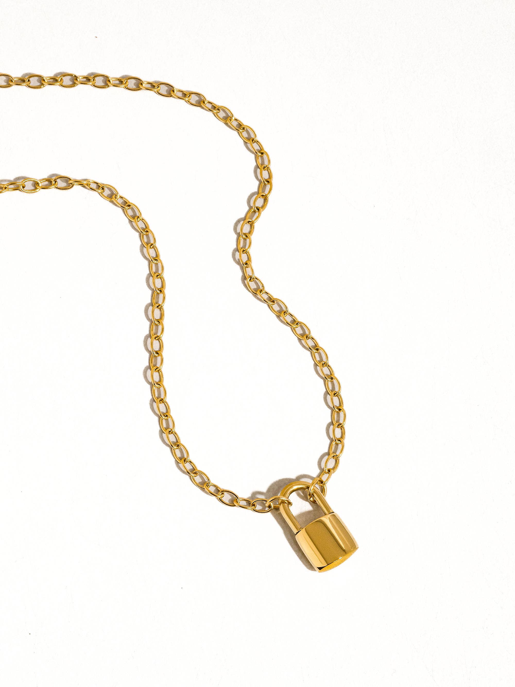 Gold necklace with a lock pendant on a white background