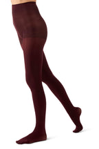 A side profile view of a person's legs wearing opaque wine tights against a plain white background.
