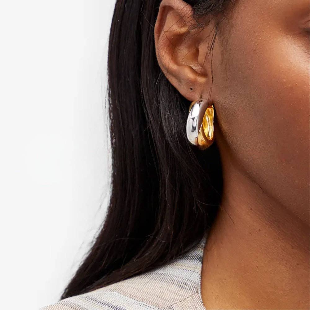 Close-up of a woman wearing a gold and silver plated mixed hoop earring.