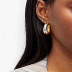 Close-up of a woman wearing a gold and silver plated mixed hoop earring.