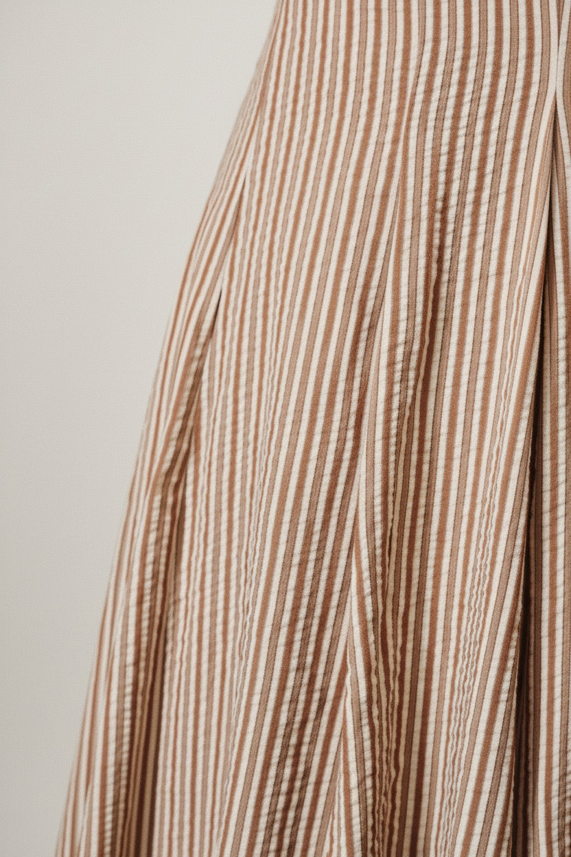 A close-up of a vertically striped fabric with alternating thin brown and off-white stripes, showing a soft seersucker texture.