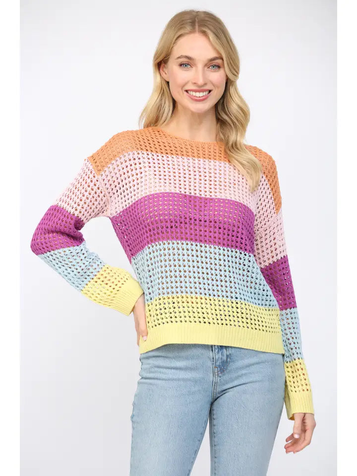Woman wearing an open weave color block striped sweater on a white background