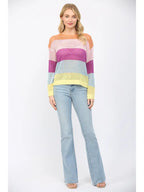 Woman wearing an open weave color block striped sweater and jeans on a white background