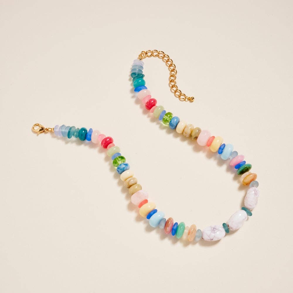Colorful beaded necklace with a gold chain on a beige background