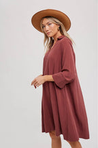 Woman wearing a wine-colored dress and brown hat on a white background