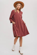 Woman wearing a wine-colored dress, white boots, and a brown hat on a white background