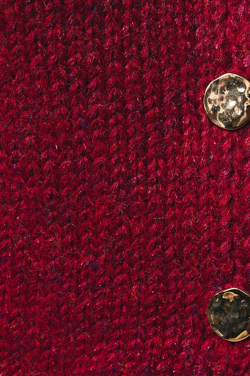 Close-up of a red knit fabric with gold buttons.