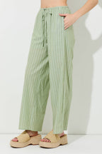 Woman wearing pin stripe green and ivory wide leg pants on grey background