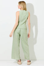 Woman wearing pin stripe green and ivory wide leg pants on grey background