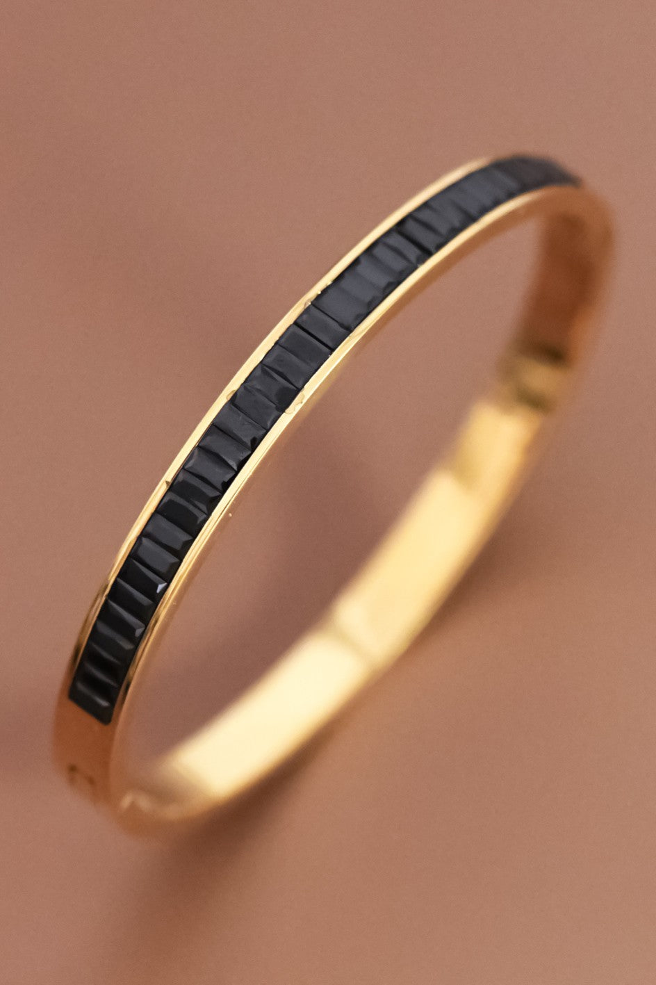 18K gold-plated bracelet with black crystal inlay on a brown background