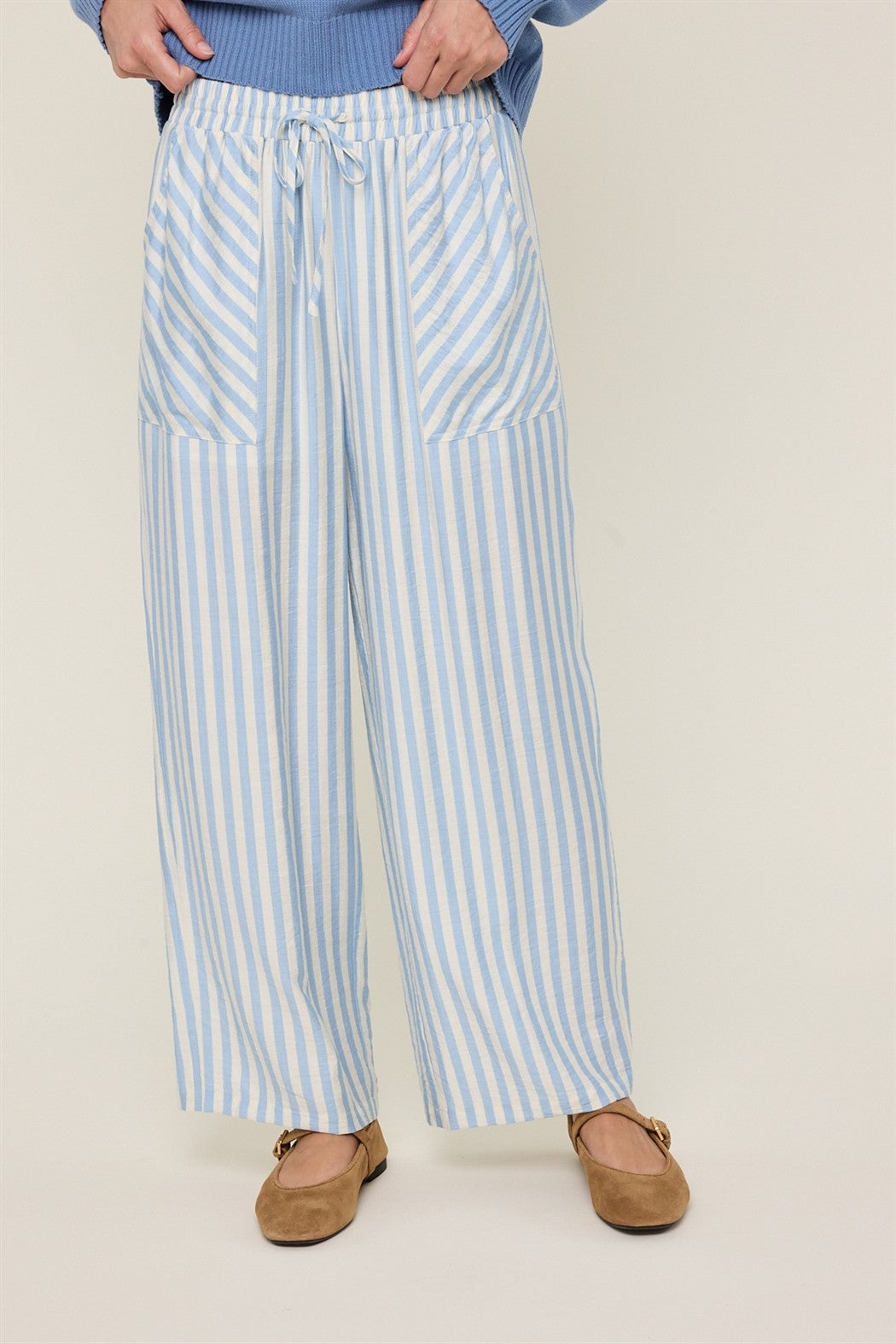 Woman wearing sky blue and cream striped wide-leg pants on a plain background
