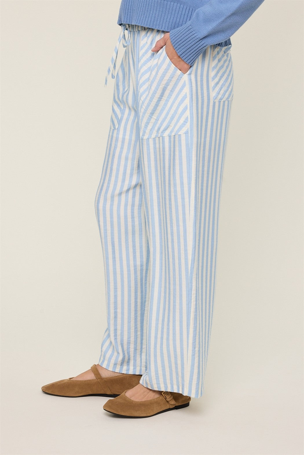 Woman wearing sky blue and cream striped wide-leg pants on a plain background