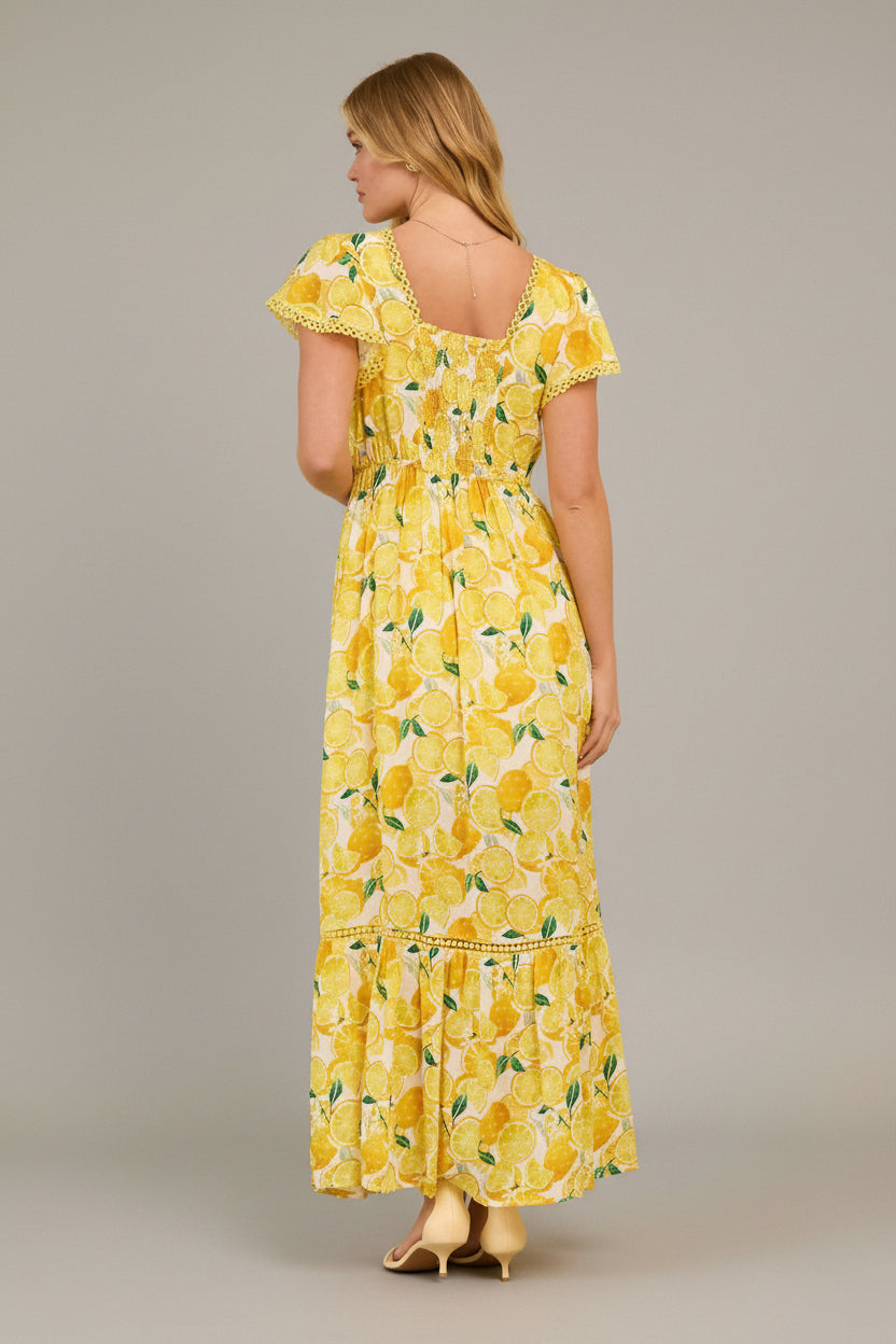 Back view of a woman wearing a yellow lemon print dress in a living room setting